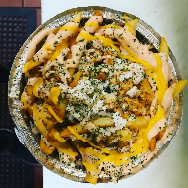Moruss Seafood's loaded fries with cheese sauce, pink sauce, crab meat, and parsley in a foil pan.