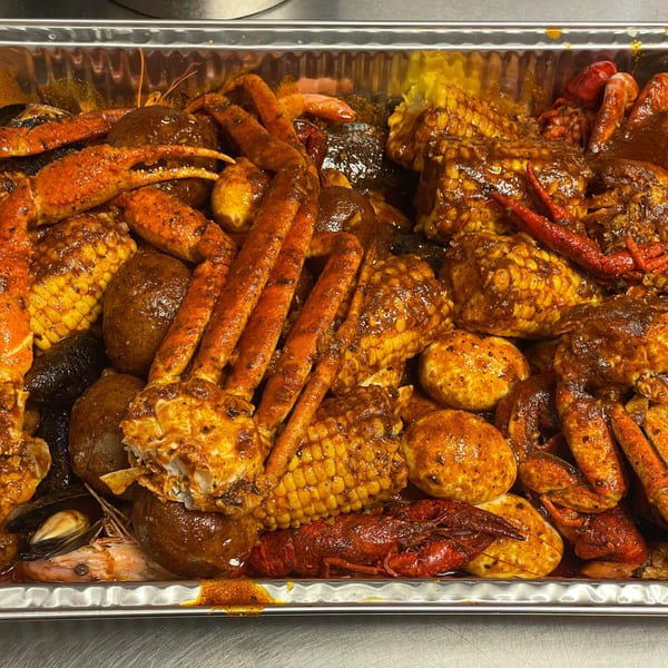 A large tray of Moruss Seafood boil with crab legs, corn, potatoes, and crawfish.